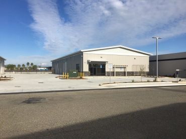 Modern industrial building with large parking area.