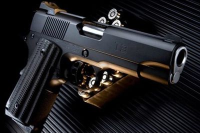 A black semi-automatic pistol with bullets on a textured surface.