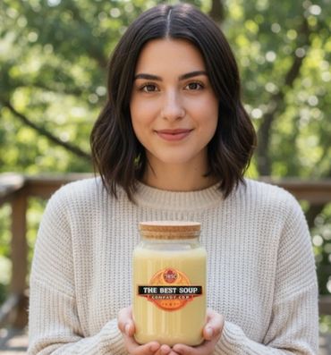 Woman holding a jar of creamy soup labeled 'The Best Soup Company'.
