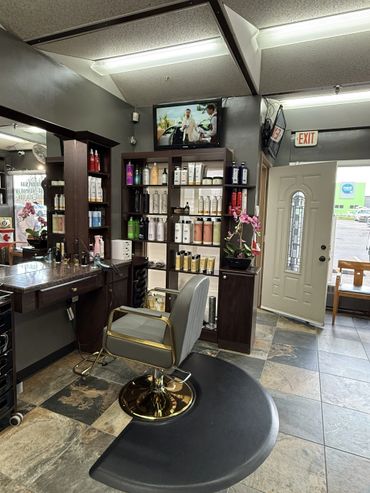 Interior of a modern hair salon with a styling chair and product shelves.