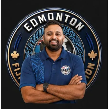Man in blue polo with Edmonton Fiji Soccer Association logo, smiling confidently.