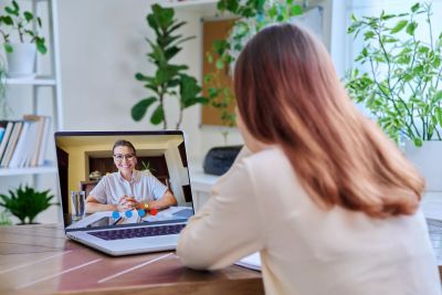 Woman video chatting on laptop with a smiling woman.