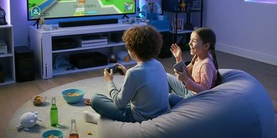 Two children play video games together on a couch in a cozy living room.