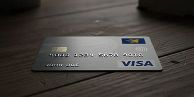A Visa credit card with the name John Doe on a wooden surface.