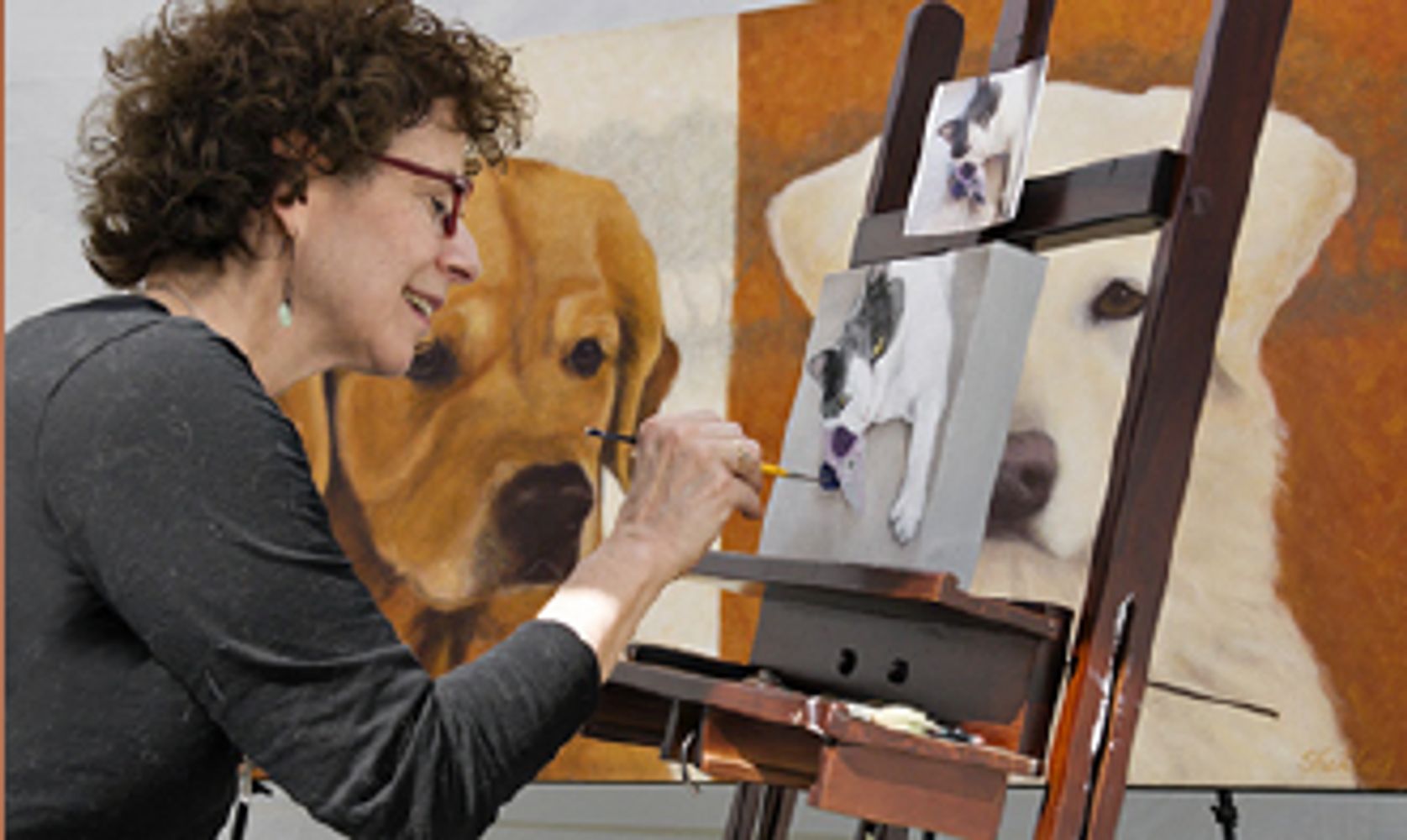 Shelley Lowell painting a portrait 
of a cat with her painting of dogs 
in the background.