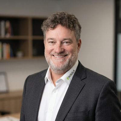 Smiling man in business attire with curly hair and beard in office setting.
