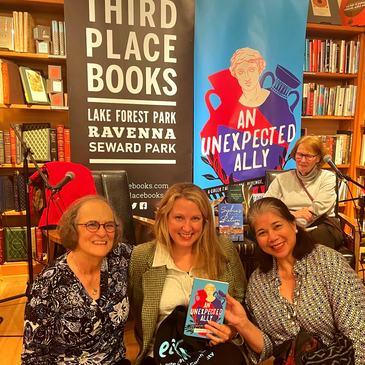 3 women smiling at Third Place Books, holding a a book, An Unexpected Ally, by Sophia Kouidou-Giles