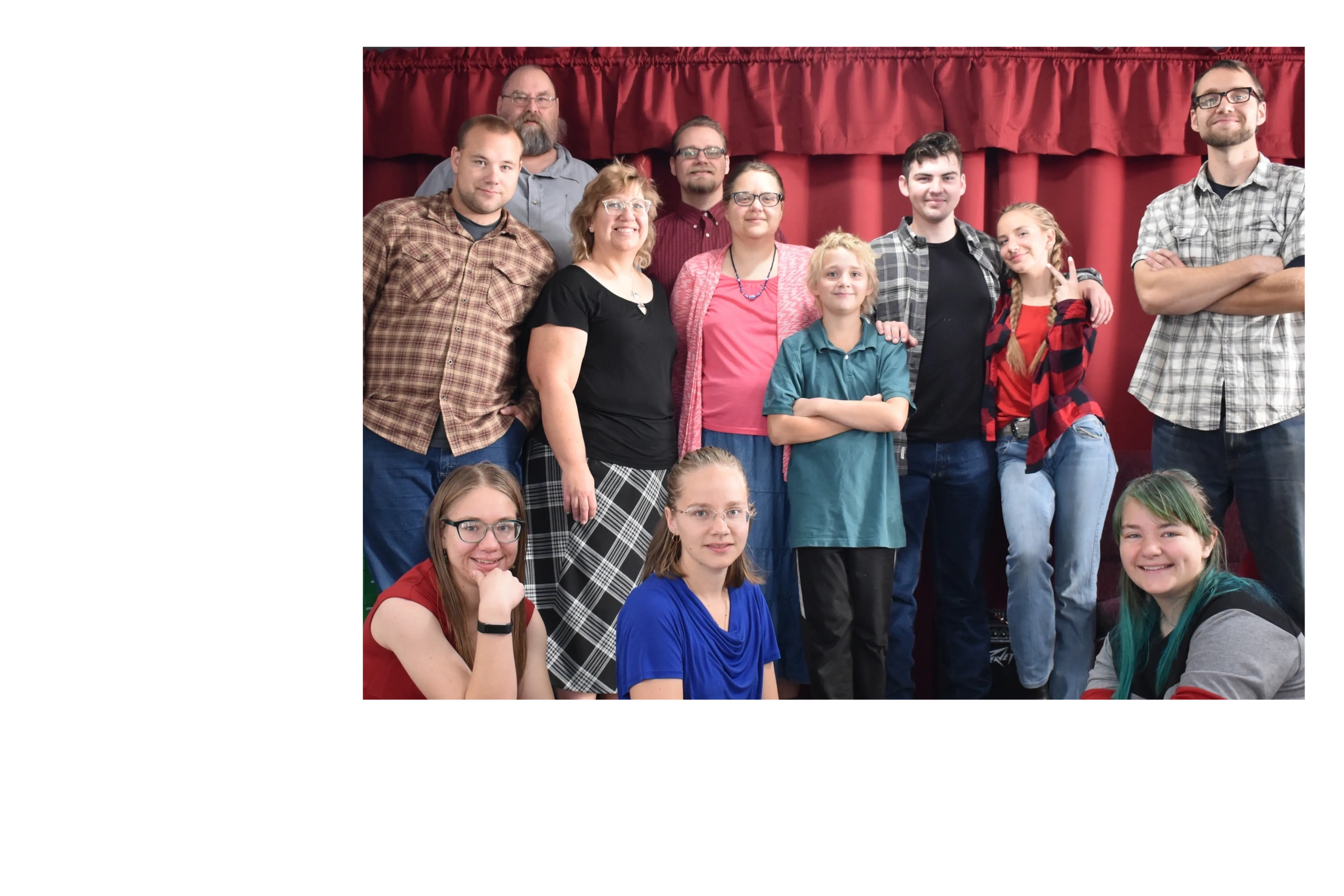 A diverse group of people posing cheerfully in front of a red curtain.