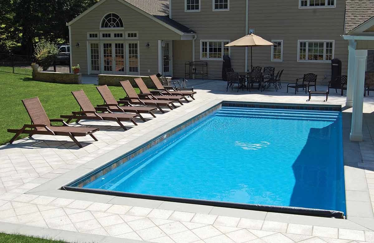 Modern backyard with a rectangular swimming pool and lounge chairs.