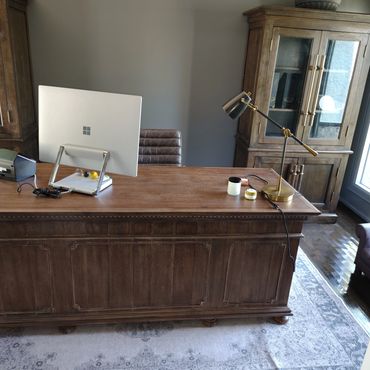 A wooden office desk with a computer and lamp in a cozy room.