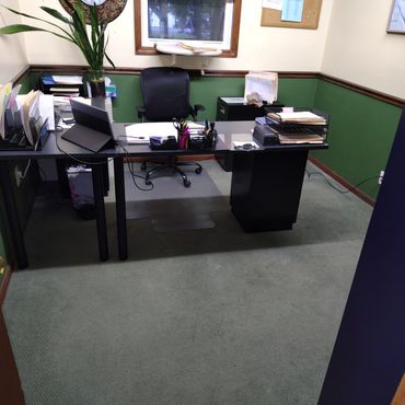 Organized office desk with chair, files, and office supplies in a green and beige room.