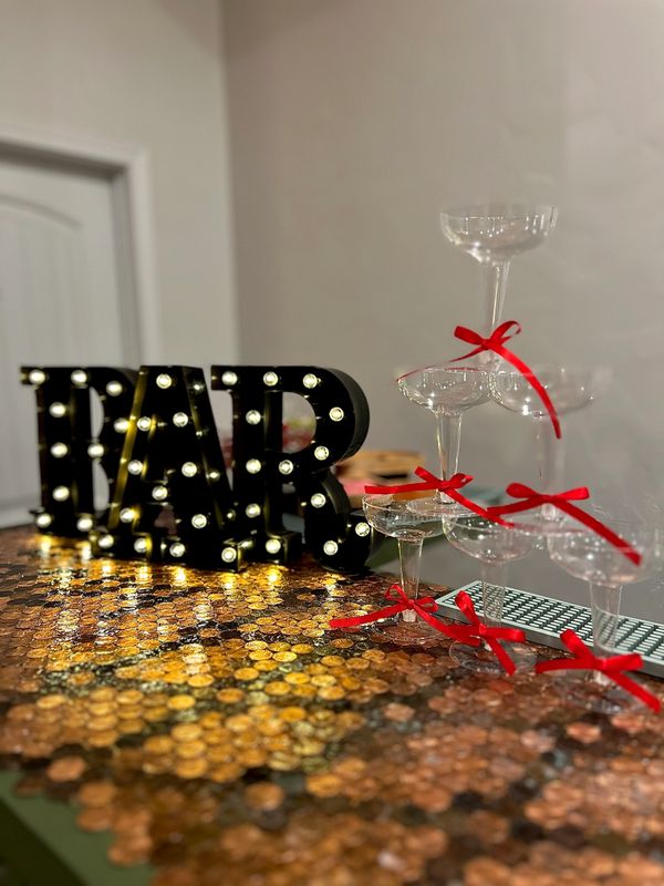 Bar setup with illuminated 'BAR' sign and champagne glasses tied with red ribbons.
