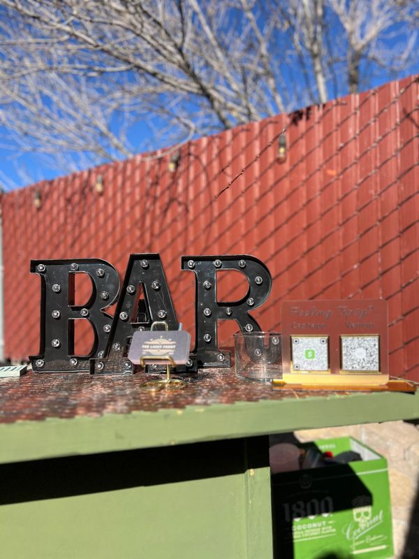 Outdoor bar setup with illuminated BAR sign and digital tip payment options.