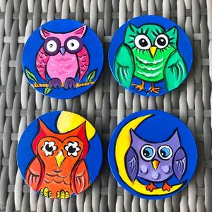 Four colorful owl illustrations on round blue backgrounds placed on a woven surface.