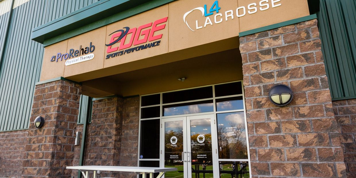 Entrance to a sports and physical therapy facility with picnic benches outside.