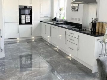 Modern white kitchen with glossy marble floor and black countertops.