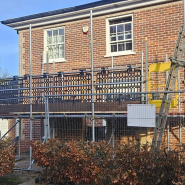 Brick house with scaffolding and clear blue sky.
