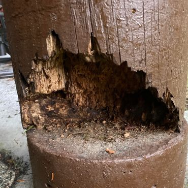 Close-up of a wooden post with severe rot and decay near its base.