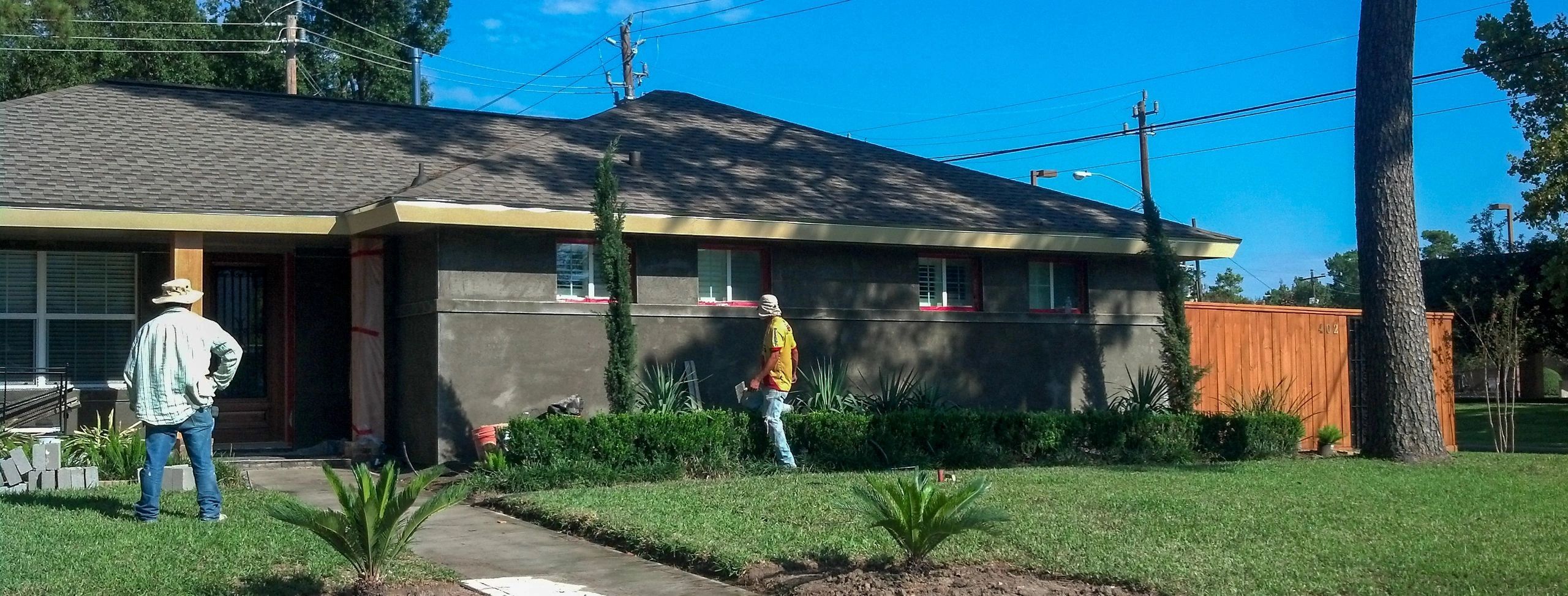 One story 60's suburban house. Low roofs and facade is covered on a gray/black cement substrate.