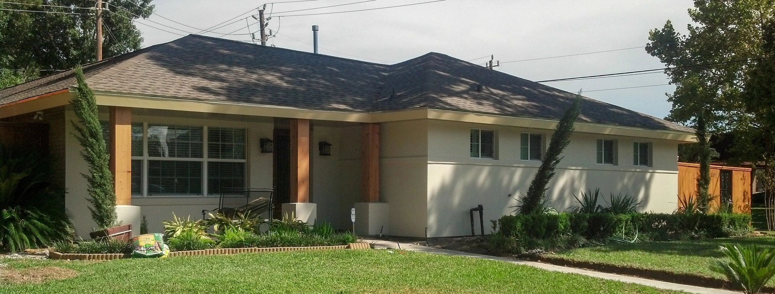 One story 60's suburban house, modern looking. Low roofs and smooth white/cream stucco facade.