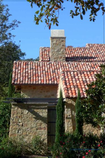 Side detail of a stone house, stone has different shades of brown, smooth carved stone accents.