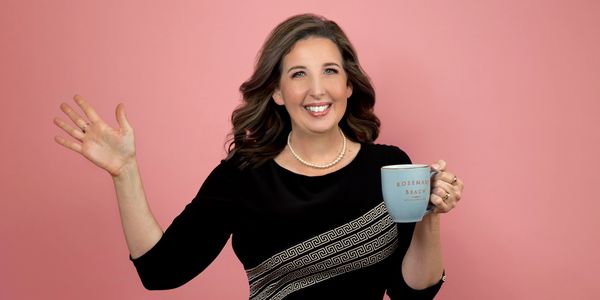 TK waving and smiling with a coffee cup.