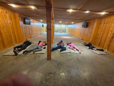 People lying on mats in a wooden-paneled room.
