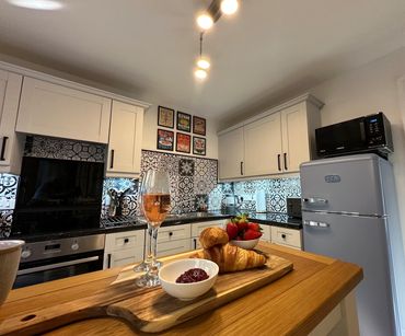 Modern kitchen with croissants, strawberries, and a drink on a wooden board.