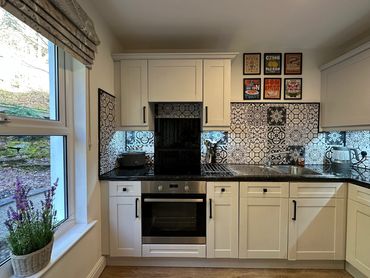 Modern kitchen with patterned tile backsplash and white cabinets.