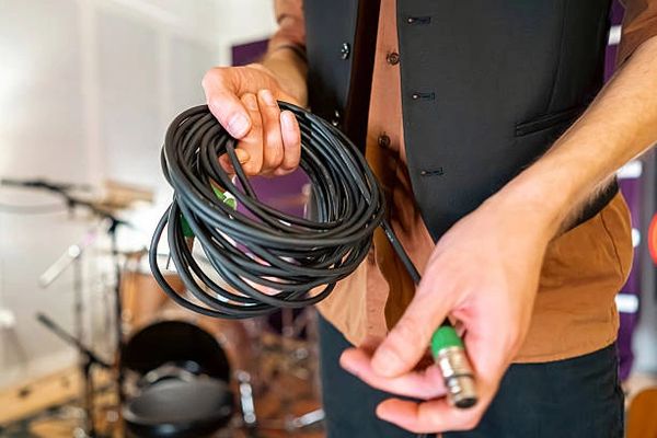 Hands holding coiled audio cable.