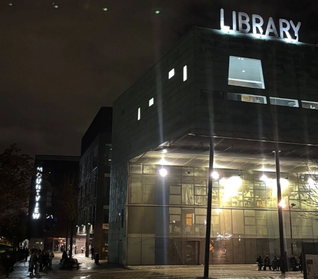 Night view of a modern library building with illuminated signage.