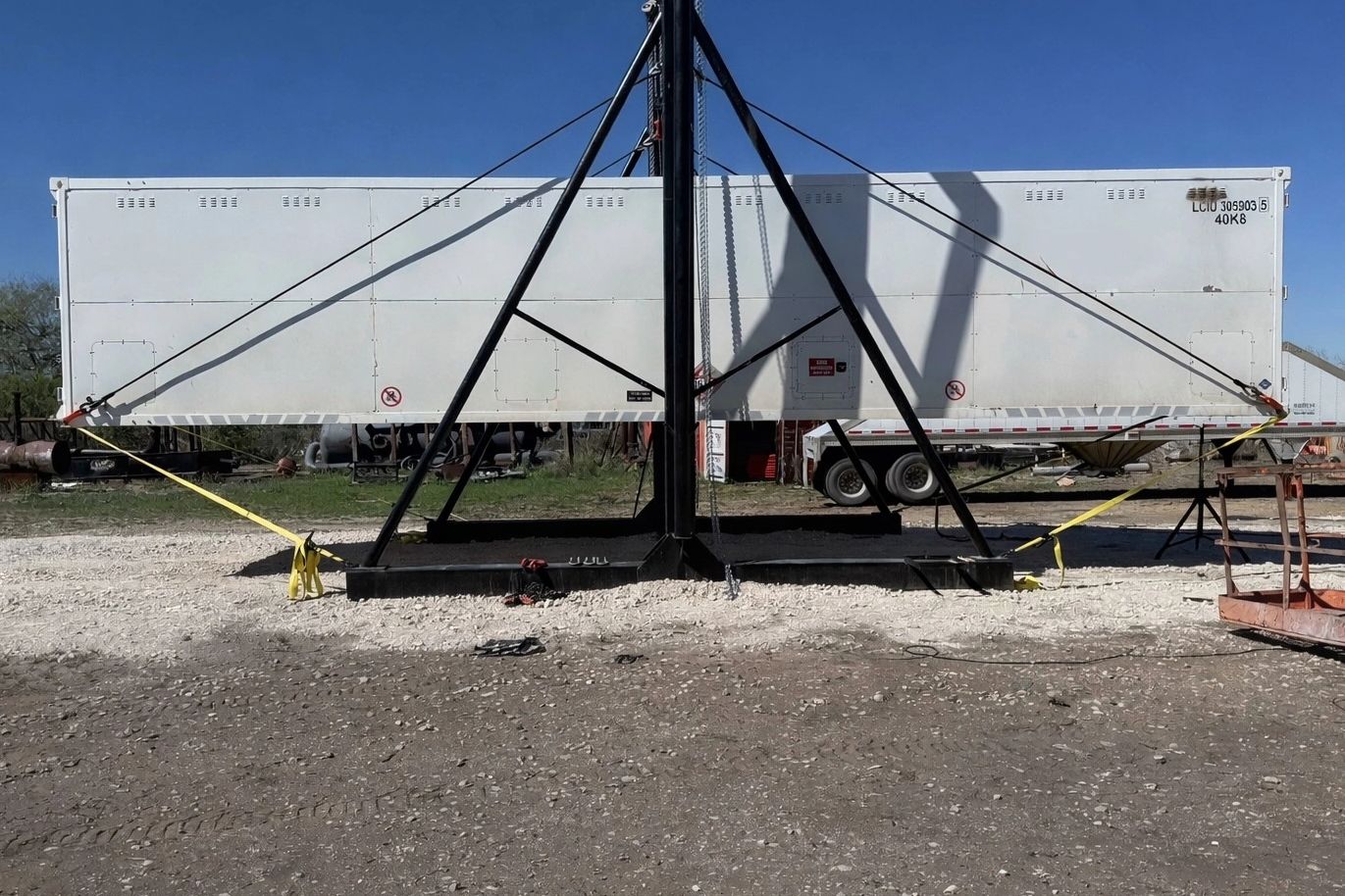 Large white trailer supported by a black metal frame outdoors.