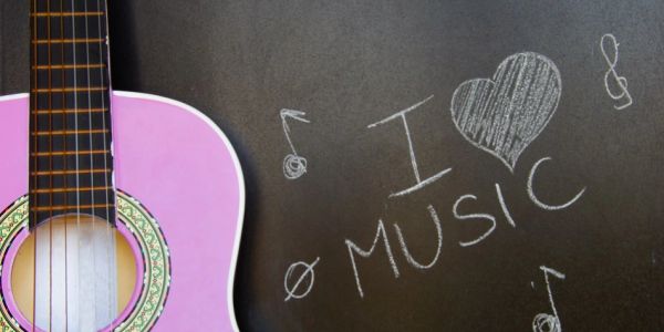 Pink guitar beside a chalkboard with 'I love music' and notes drawn.