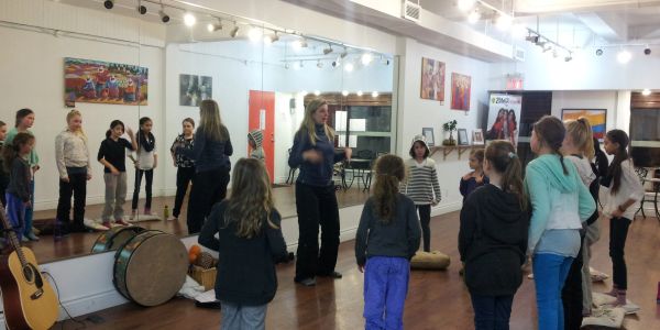 Children and instructor in a music or dance class inside a studio.