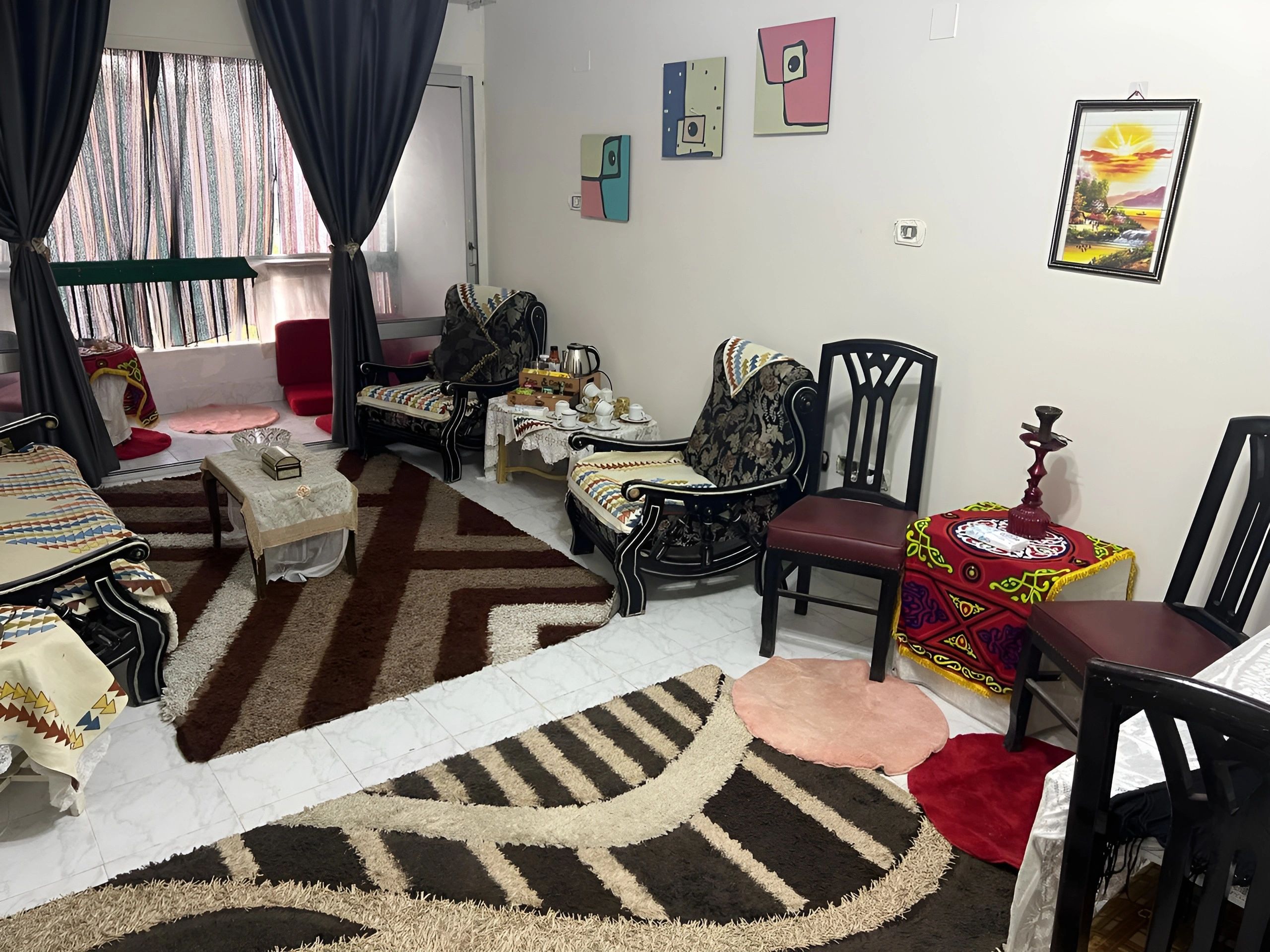 A cozy living room with patterned armchairs, a coffee table, colorful decor, and framed wall art.