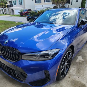 A glossy blue BMW in a driveway