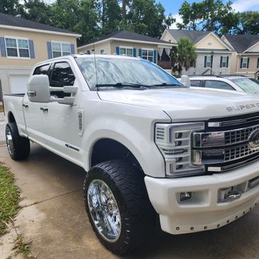 A glossy white ford f 250 truck sitting in a driveway