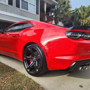 A glossy red Chevy Camaro sitting in a driveway