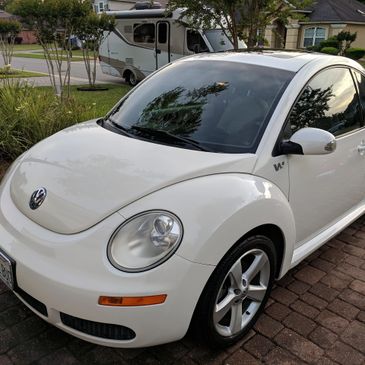 A white Volkswagon Beetle in a driveway