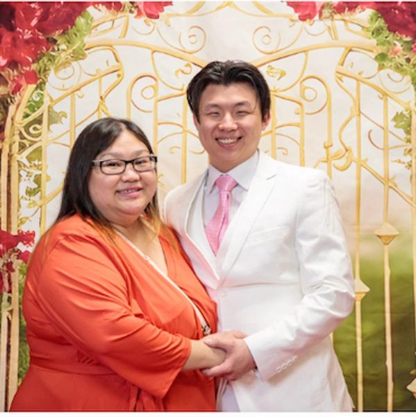 Couple smiling in front of decorative gate.