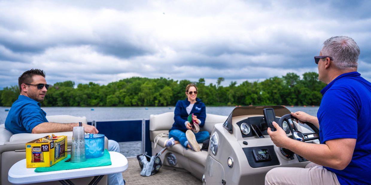Three people relaxing on a boat with snacks and drinks.