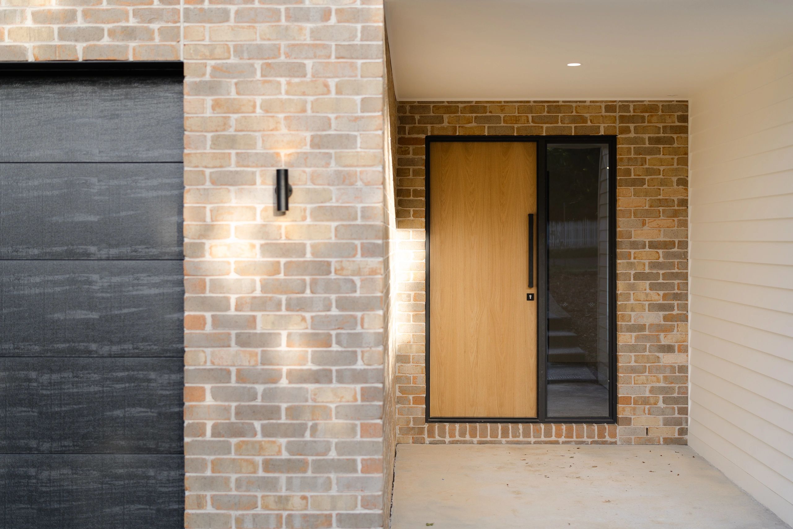 Modern house entrance with wooden door and brick walls.