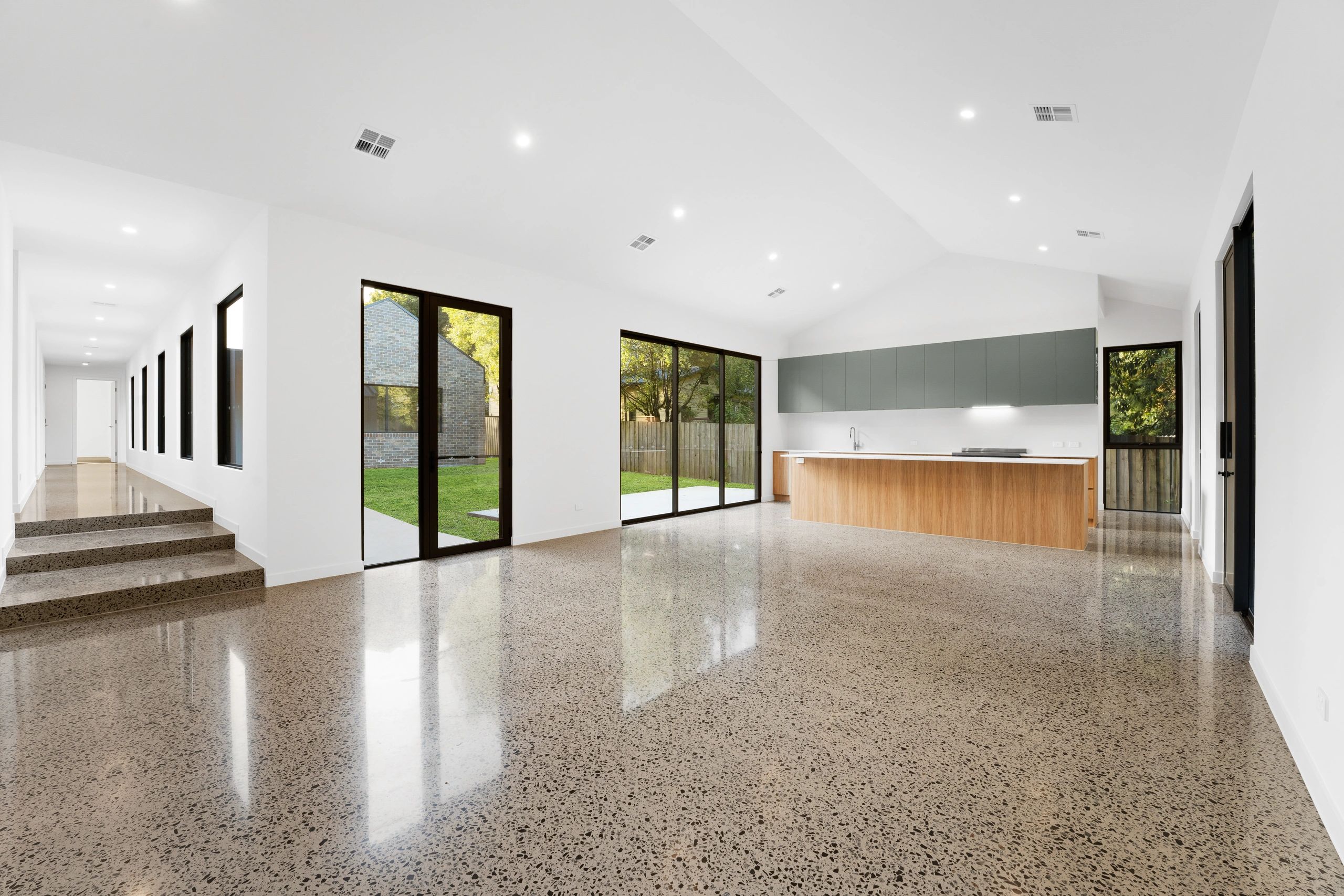 Spacious modern kitchen with polished concrete floors and large windows.