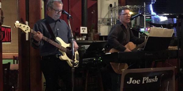 Two musicians performing live with guitar and bass in an intimate venue.