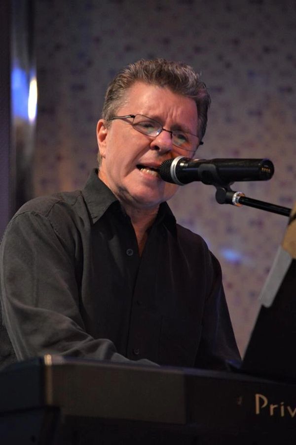 Man singing and playing keyboard with microphone.