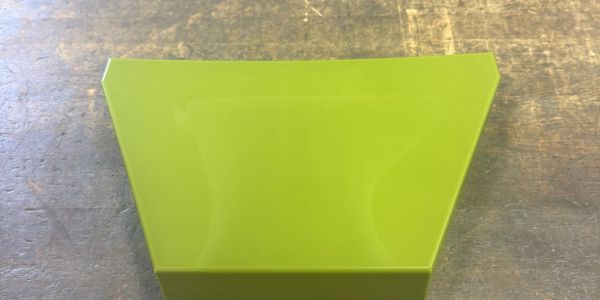 Bright green translucent geometric shape on a wooden surface.