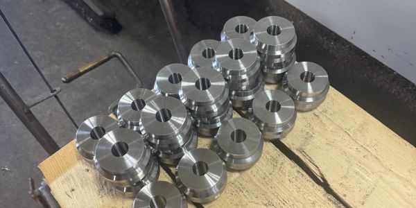 Stack of shiny metal discs with central holes on wooden surface.