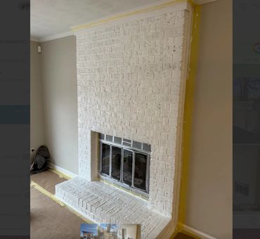 A white-painted brick fireplace with glass doors in a room under renovation.