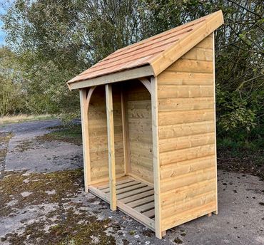 A wooden outdoor shelter with a slanted roof on a concrete surface.