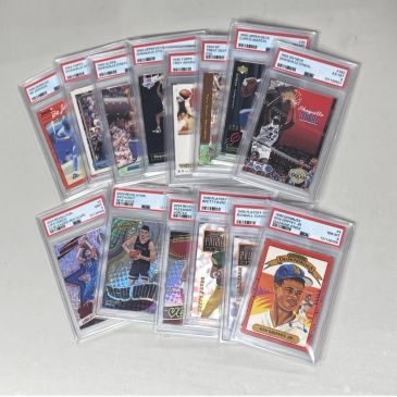 A collection of graded basketball and baseball trading cards in protective cases.